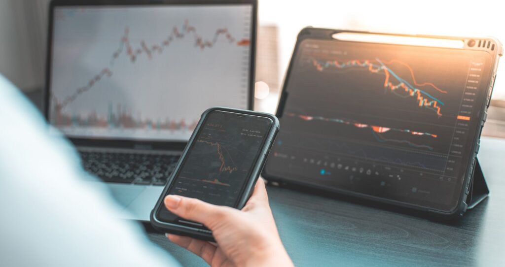 man looking at his investment accounts on his pc, laptop, and mobile phone