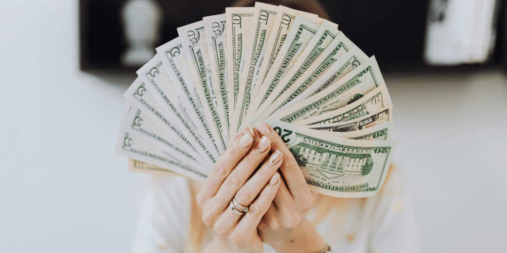 woman holding a large stack of cash folded like a fan