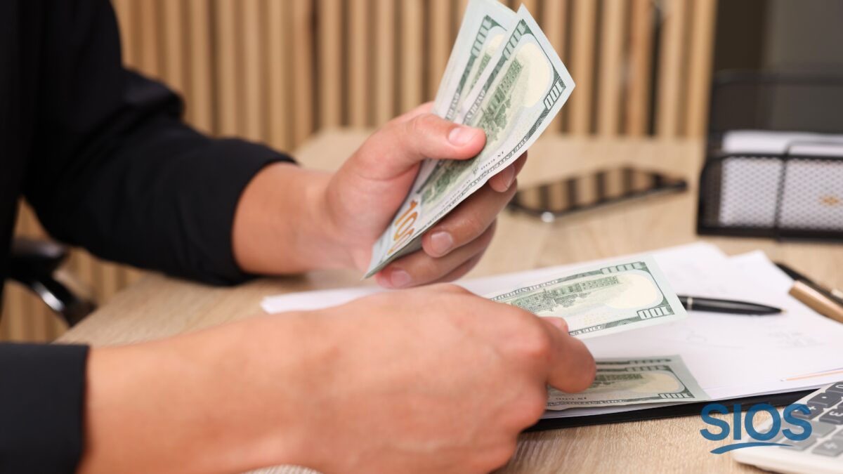 Man organizing cash on his desk while paying bills and planning finances